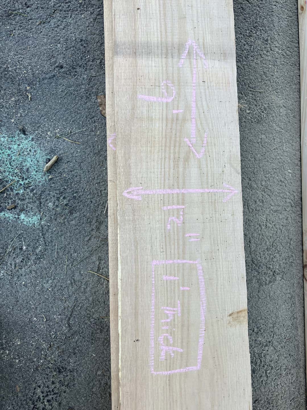 A sawn board with its dimensions written across the face in chalk.